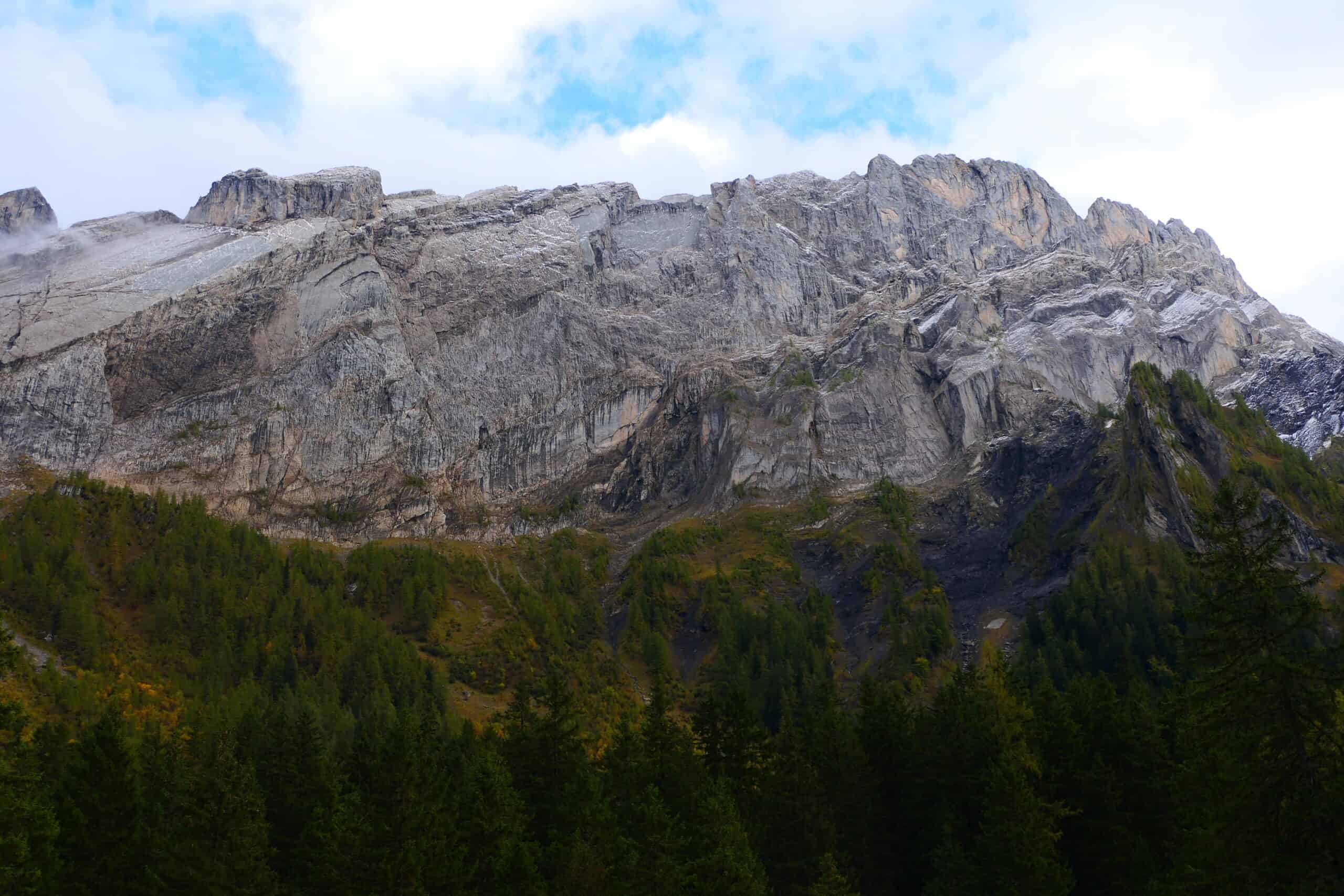 Vue d'une montagne rocheuse avec forêt dense au pied.