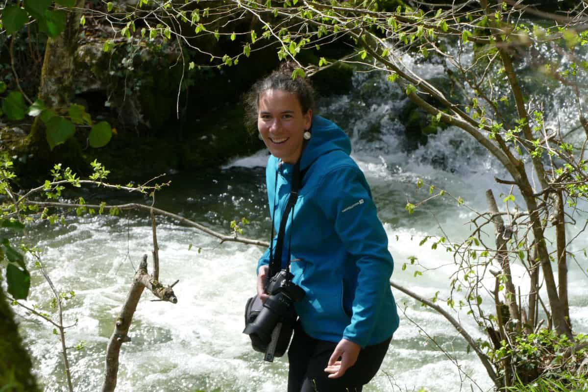 Femme en nature près d'une rivière avec appareil photo.
